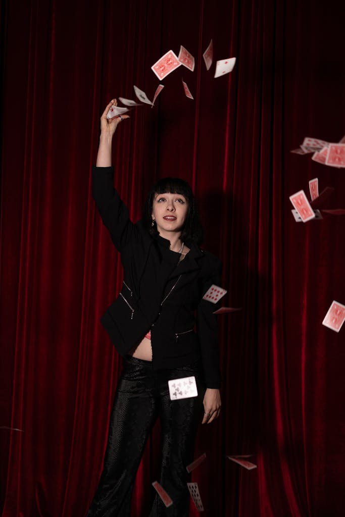 A woman in black jacket and black pants throwing cards