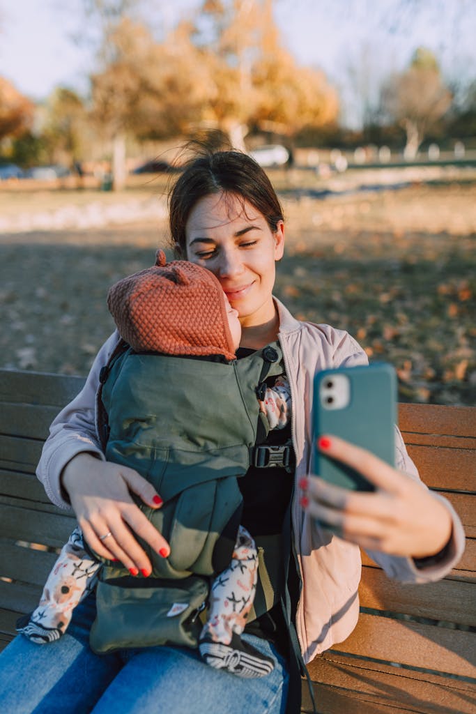 A Woman Sitting on the Bench while Taking Selfie with Her Baby