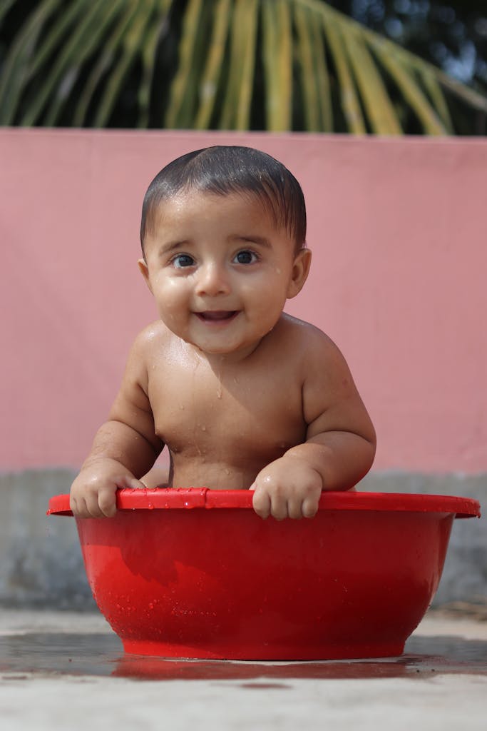 Baby Having Bath in a Red Bowl