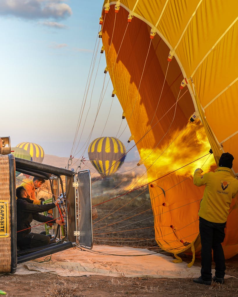 Group of people making fire and launching colorful hot air balloons in clear sky