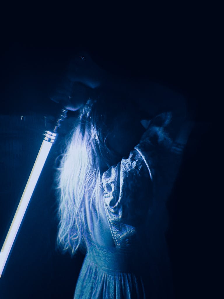 Woman in a Dress Holding a Blue Lightsaber behind Her Back