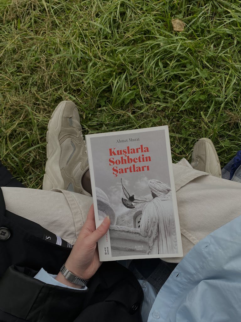 Woman Sitting on the Grass with a Book in Hand